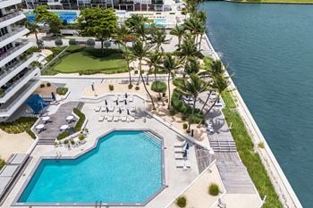 Waterfront pool deck with lounge chairs and palm trees